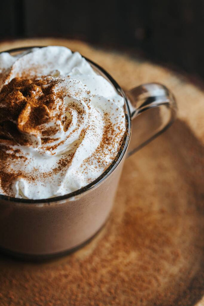 A vertical top view of a glass of hot chocolate on a wooden board, with cream on top - Foto, Imagen