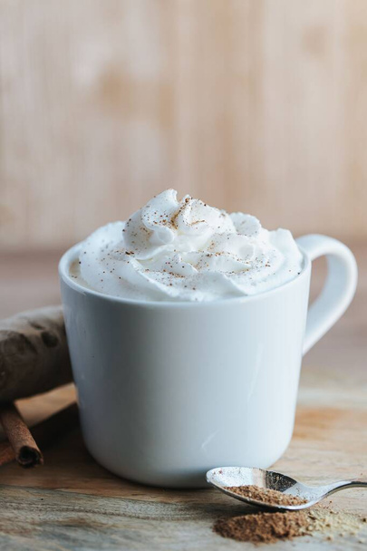 A vertical shot of a cup of hot chocolate on the wooden background - Fotó, kép