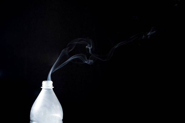 The smoke coming out of a plastic bottle on black background -  aromatherapy concept - Photo, image
