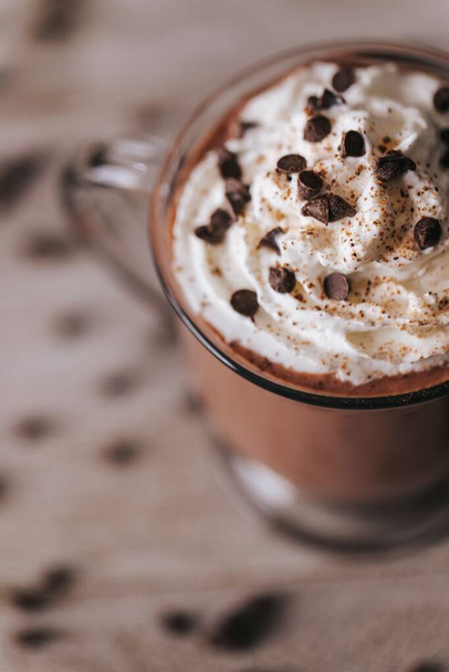A vertical shot of a cup of hot chocolate on the wooden background - Фото, изображение
