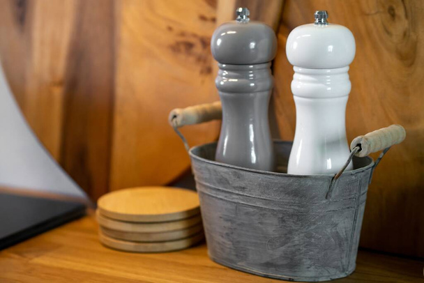 A closeup shot of gray and white salt and pepper grinders on a wooden table - Fotoğraf, Görsel