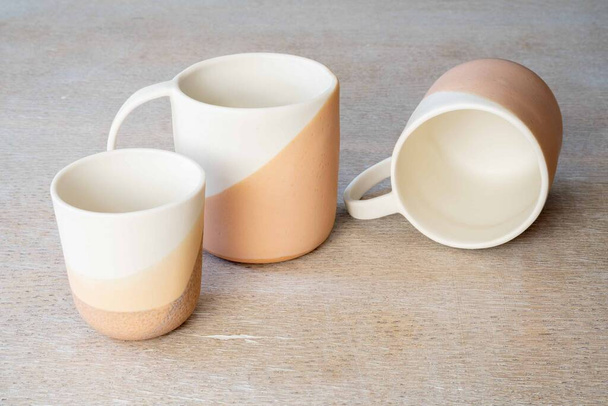 Different sizes of luxury white and brown ceramic dipped mugs on marble background - Fotoğraf, Görsel