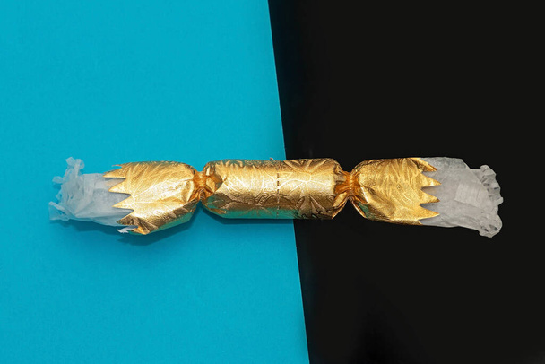 Festive Christmas fire cracker wrapped in gold paper tube on two sided color background - Φωτογραφία, εικόνα