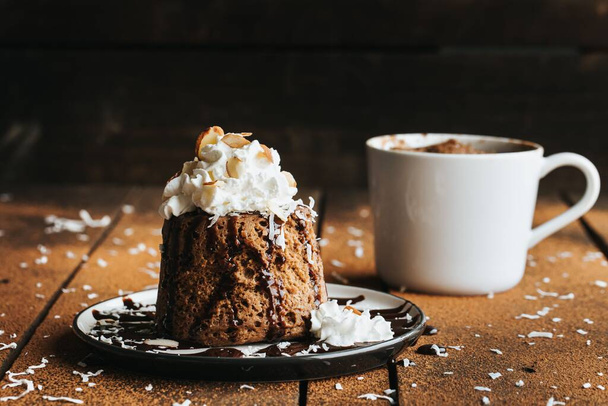A closeup shot of a chocolate cake and a white cup on the wooden background - Foto, afbeelding