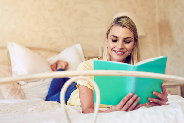 Czytam dla relaksu. młoda kobieta czytająca książkę leżąc na łóżku - Zdjęcie, obraz