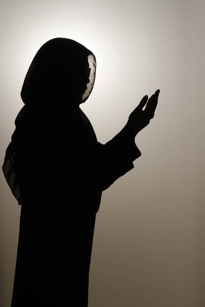 Η σιλουέτα μιας μουσουλμάνας στην Άβαγια προσεύχεται με τα χέρια ψηλά στον αέρα. Θρησκεία προσευχής. Ηνωμένα Αραβικά Εμιράτα - Φωτογραφία, εικόνα