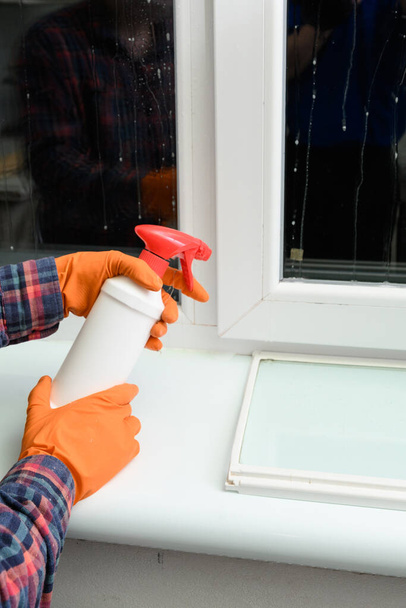 Pulverización de la droga contra el moho dañino en la ventana, los productos químicos corren por el vidrio de la ventana. - Foto, Imagen