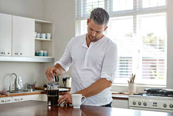 Hacer el brebaje perfecto. un hombre tomando café por la mañana en casa - Foto, Imagen