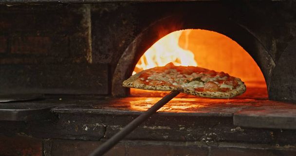 Pizza coming out from the oven close up - 写真・画像