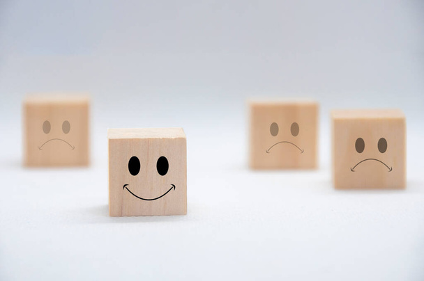 Szczęśliwe i smutne emotikony na drewnianych kostkach z białą okładką tła. Zadowolenie klienta i koncepcja oceny - Zdjęcie, obraz