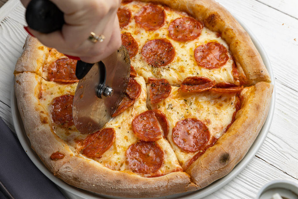 delicious pizza on a white wooden table. close-up - Fotó, kép