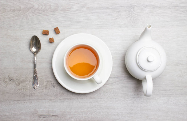 Xícara de chá e bule de chá, colher, açúcar, em um fundo de madeira leve - Foto, Imagem