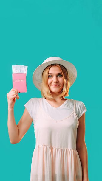 Travel agency. Holiday journey. Happy smiling beautiful woman in white holding passport with tickets traveling abroad isolated on turquoise empty space background. - Photo, Image