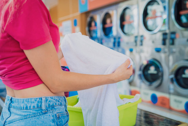 Young beautiful woman washes and dries clothes in the laundry. - Photo, Image
