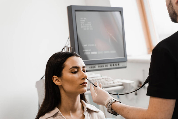 Médecin ORL utilisant le fibrolaryngoscope pour examiner et traiter le nez. Spécialiste ORL diagnostique et traite le larynx et le pharynx, tels que l'enrouement, les nodules de cordes vocales, les tumeurs, les infections et l'inflammation - Photo, image