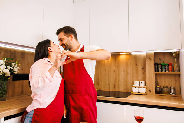 Affectionate couple wearing pajamas kissing each other in their kitchen at home in the morning. High quality photo - Zdjęcie, obraz