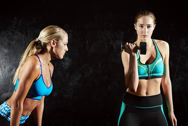 Murskaat sen, jatka vain. kaksi nuorta naista treenaamassa painoilla kuntosalilla - Valokuva, kuva