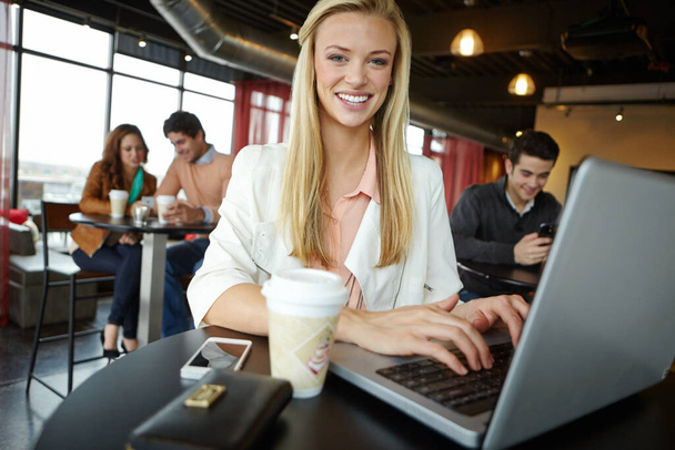 Updating my blog quickly. A beautiful young woman using her laptop in a busy coffee shop - Fotoğraf, Görsel