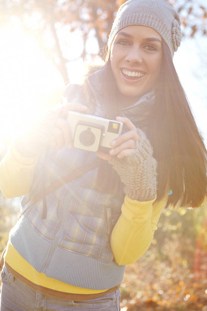 Enjoying the Autumn Wonderland. Portrait of a smiling young woman standing with her camera in the outdoors - Foto, immagini
