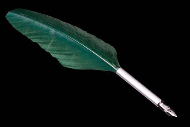 Green feather quill pen. Isolated on black background. - Photo, Image