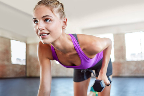Smart girls use dumbbells. a young woman working out with weights at the gym - Photo, image