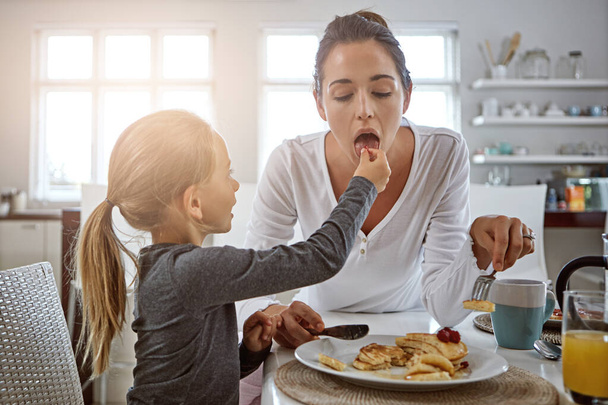 Laisse-moi m'occuper de ta mère. une mère et sa fille qui prennent le petit déjeuner à la maison - Photo, image