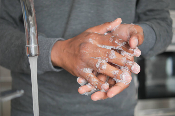 молодой человек мыл руки теплой водой с мылом. - Фото, изображение