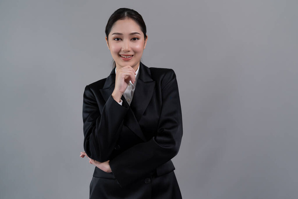 Confident young businesswoman stands on isolated background, posing in formal black suit. Office lady or manager with smart and professional appearance. Enthusiastic - Foto, imagen