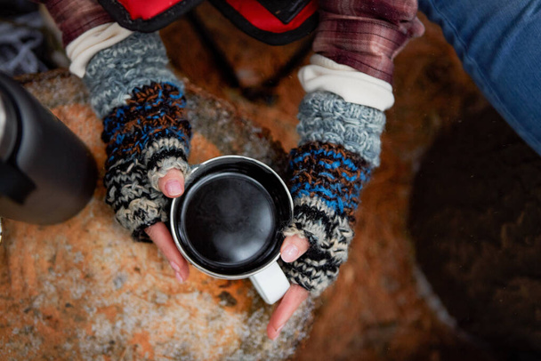 Brrr Czas na kawę. Wysokie ujęcie nierozpoznawalnej kobiety pijącej ciepły napój podczas kempingu na pustyni zimą - Zdjęcie, obraz