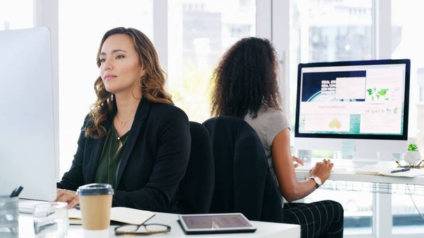 Ligado à produtividade. duas jovens empresárias usando seus computadores em um escritório moderno - Foto, Imagem