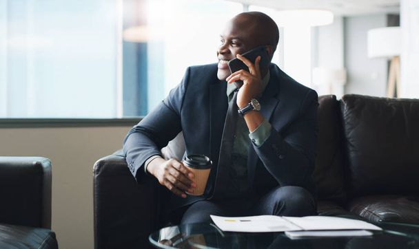 Πάντα θα λαμβάνεις καλά νέα αν είσαι δουλευταράς. ένας επιχειρηματίας που μιλάει στο κινητό του ενώ κάθεται σε ένα μοντέρνο γραφείο - Φωτογραφία, εικόνα