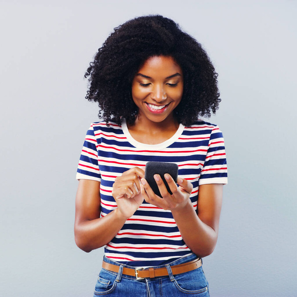 Її зв'язок з усім світом. Студійний знімок красивої молодої жінки, використовуючи смартфон на сірому фоні
 - Фото, зображення