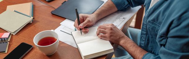 Крупним планом руки людини роблять нотатки в блокноті, сидячи на своєму робочому місці. Високоякісна фотографія
 - Фото, зображення
