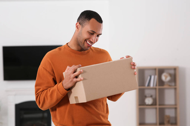 Happy young man with parcel at home. Internet shopping - Foto, imagen