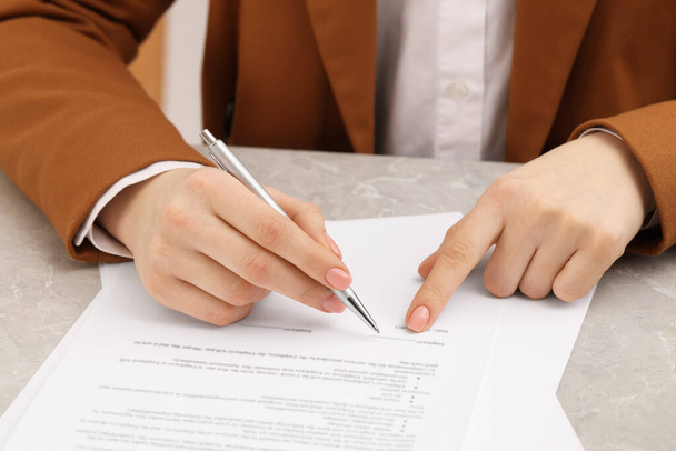 Woman signing document at table, closeup view - 写真・画像