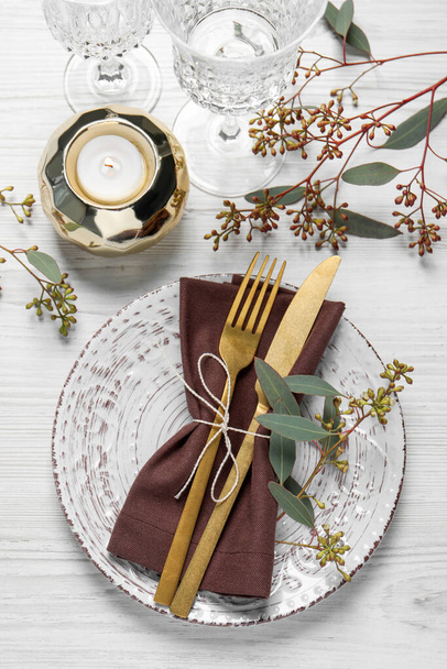 Stylish table setting with cutlery, burning candle and eucalyptus leaves, flat lay - Photo, image