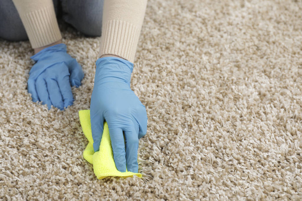 Woman in rubber gloves cleaning carpet with rag indoors, closeup. Space for text - Foto, immagini