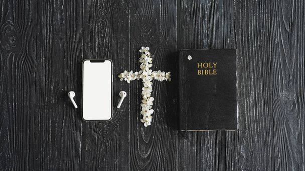 聖書崇拝のオンライン概念を勉強しなさい。教会オンライン日曜日の新しい通常の概念。木製の背景に聖書、携帯電話、イヤホン。家庭教会 - 写真・画像