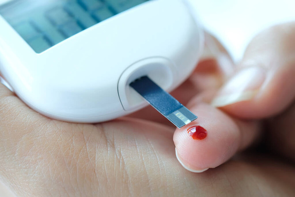 käsi tarkistaa diabeteksen ja korkean verensokerin monitorin digitaalisen painemittarin avulla. Terveydenhuollon ja lääketieteen käsite - Valokuva, kuva