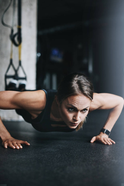 Fit is a lifestyle choice. an attractive young woman doing push ups in a gym - Foto, immagini