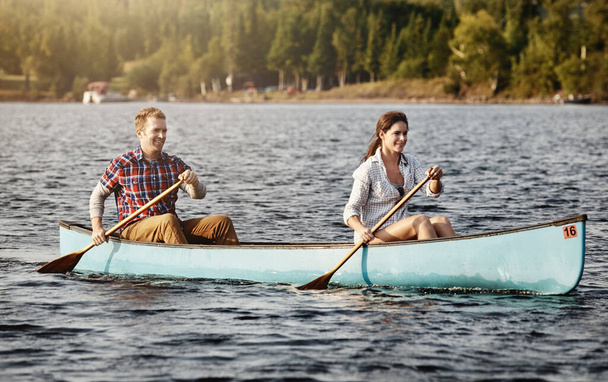 El piragüismo es aún mejor cuando se comparte. una joven pareja que va a dar un paseo en canoa por el lago - Foto, Imagen