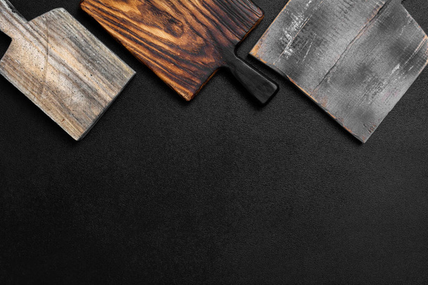 Set of old stylish wooden cutting board on a black background. Kitchenware top view. Empty space for your ready meals - Foto, Bild