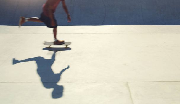Burning some wheels at the skatepark. an unrecognizable man doing tricks on his skateboard at a skate park - 写真・画像