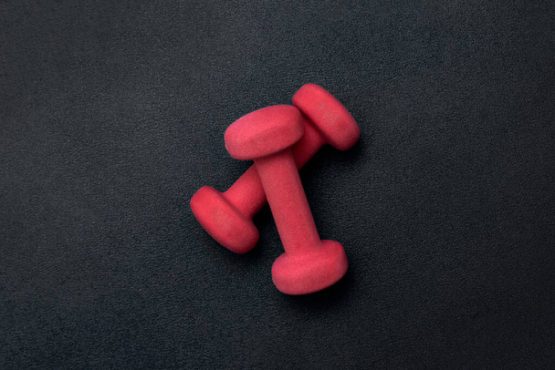Two red dumbbells on a black background. View from above. Sport equipment - Photo, Image