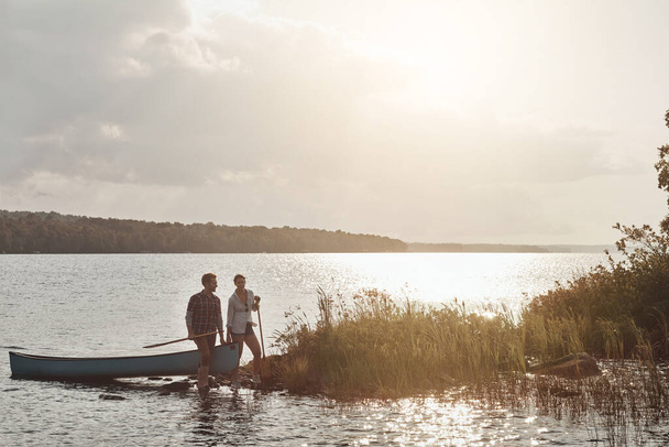 Даты их мечты включают в себя прогулку на природе. молодая пара собирается покататься на каноэ по озеру - Фото, изображение