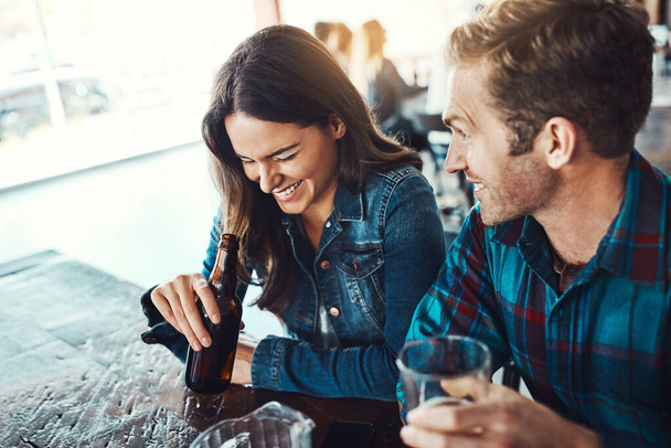 His stories have her in stitches. a happy young man and woman having beers at a bar - 写真・画像