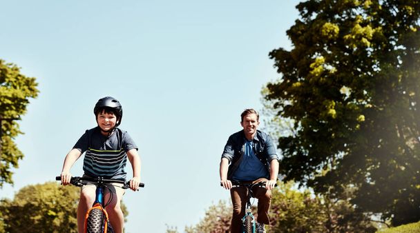 To ich zabawa do zrobienia razem. młody chłopiec i jego ojciec jadący razem na rowerach - Zdjęcie, obraz
