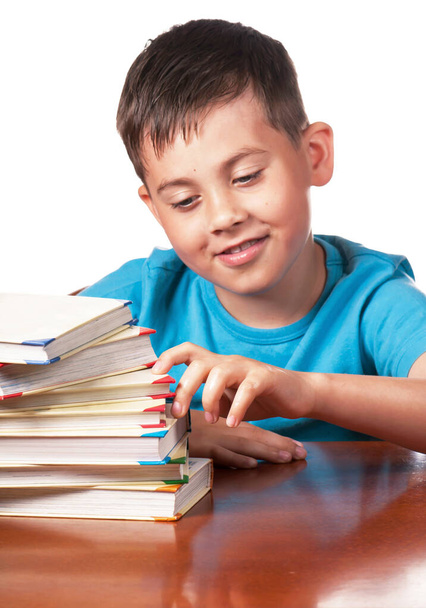 Child and books. The boy reads and plays with books. A preschooler is learning to read. Portrait of a boy on a white background - Photo, Image