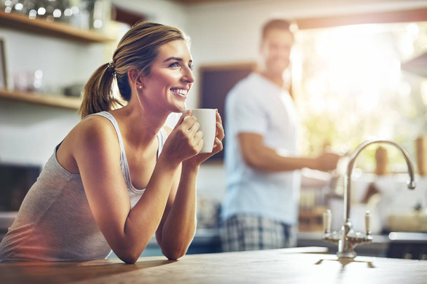 Coffee is instant happiness. a young woman having her morning coffee with her boyfriend standing in the background - Foto, Bild