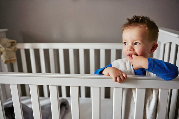Sun is up and so am I. a cute little baby boy standing in his cot - Foto, Imagem